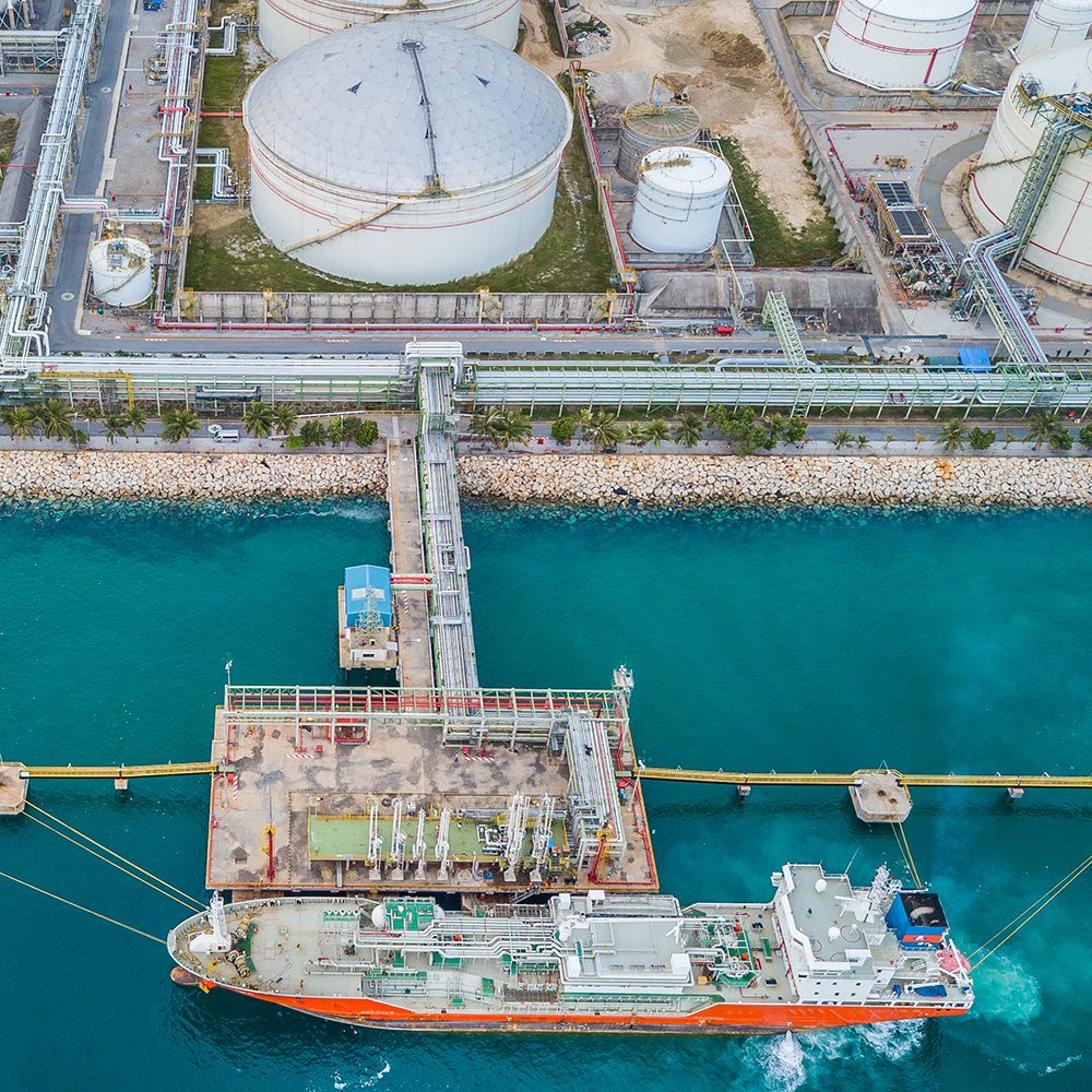 Aerial top view of oil tanker ship at the port, oil terminal is industrial facility for storage of oil and petrochemical products ready for import export business logistic and transportation.